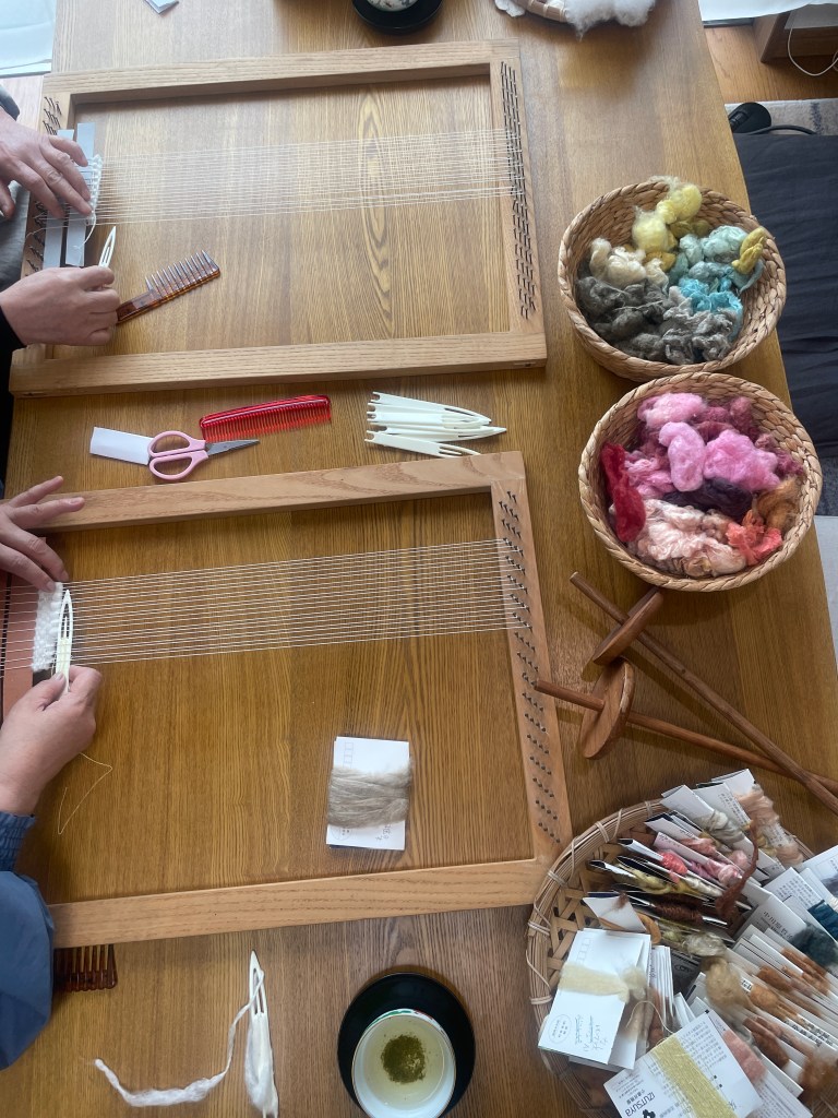 木枠に草木染めの糸を通して小さな布を織る様子